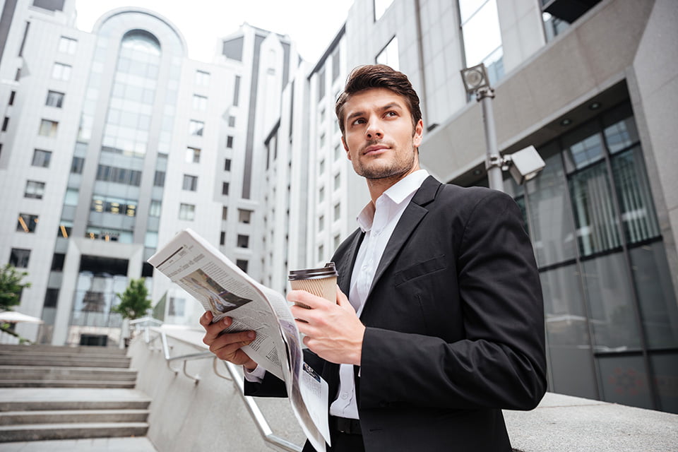 A gentleman in a fully tailored two-piece suit reading the morning paper